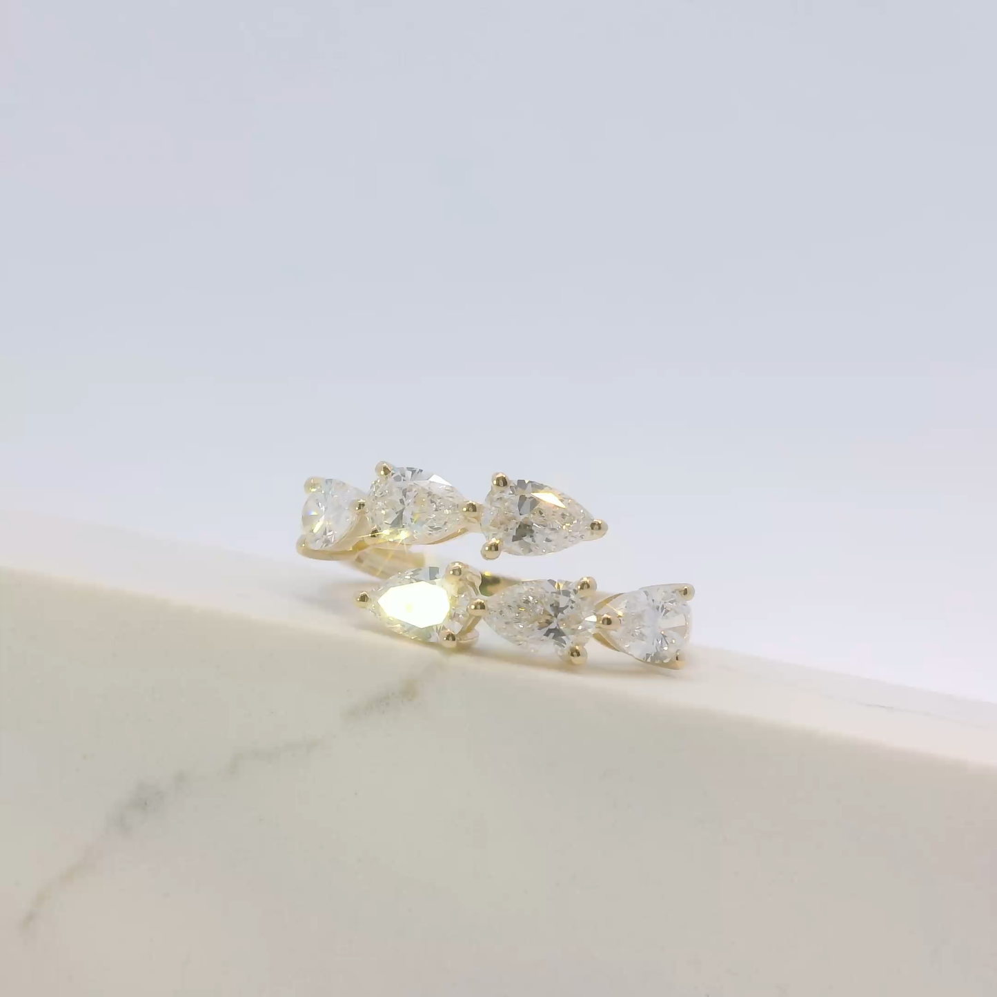 Gold earrings with clear gemstones on a light gray background