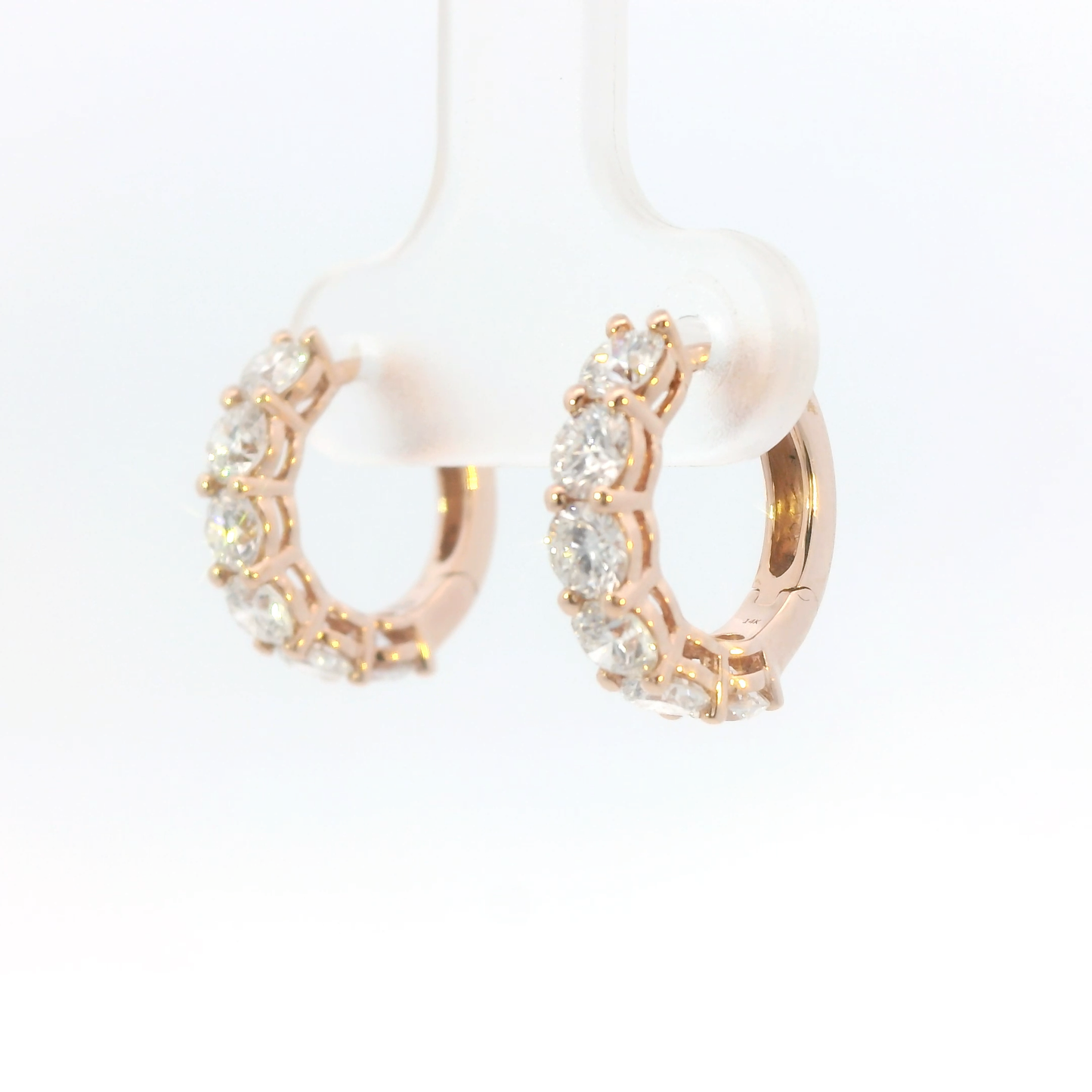 Rose gold hoop earrings with pearls and clear stones on a white background