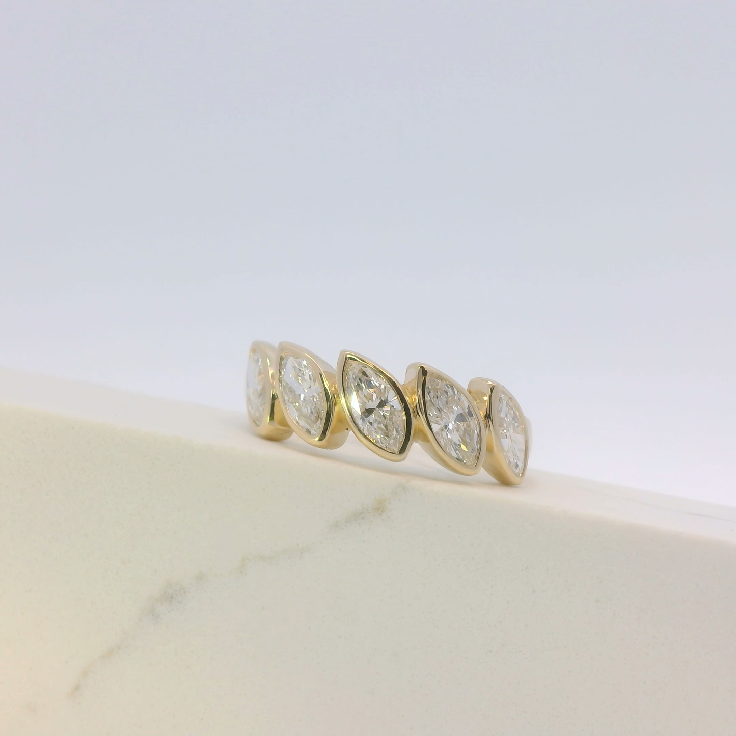 Gold ring with four diamond stones on a marble surface