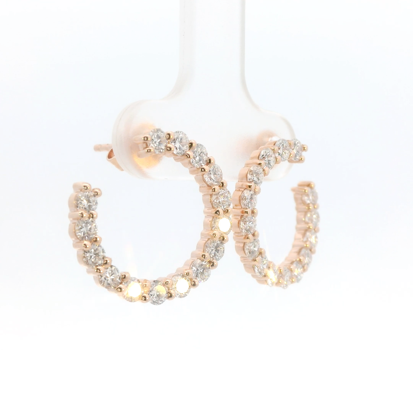 Rose gold hoop earrings with clear gemstones on a white background