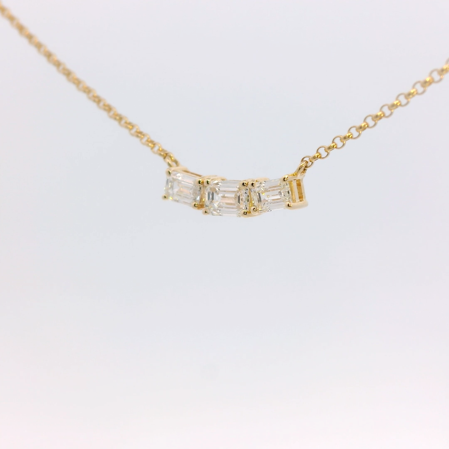 Gold necklace with a diamond pendant on a light gray background