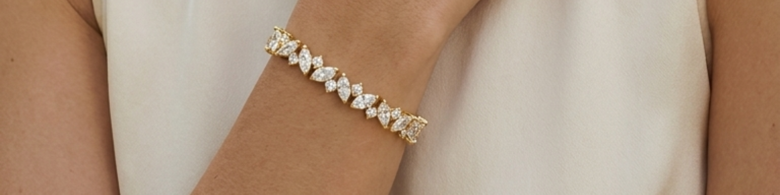 A gold marquise cut diamond tennis bracelet worn on a woman's wrist