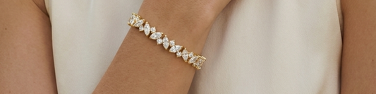 A gold marquise cut diamond tennis bracelet worn on a woman's wrist