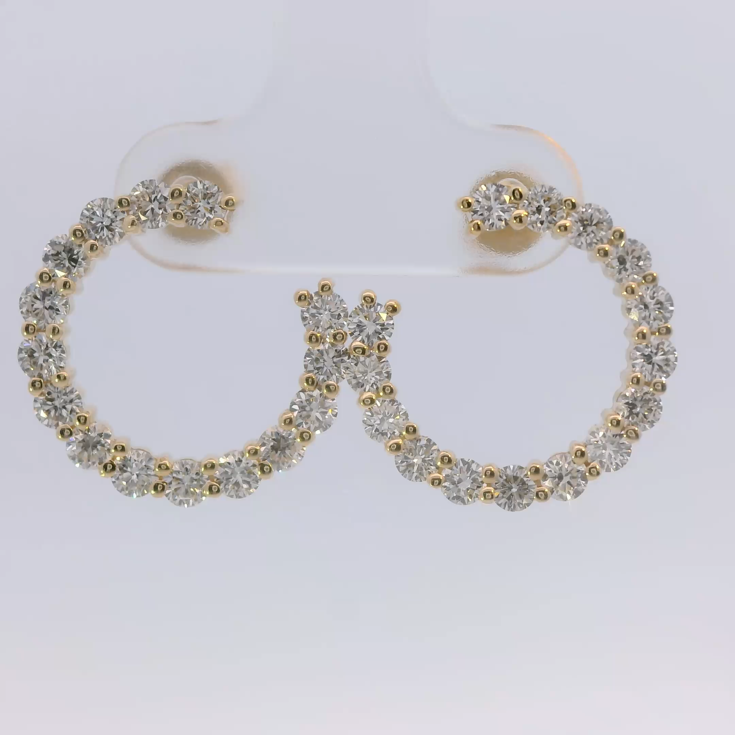 Pair of hoop earrings with gold and round diamonds on a white background