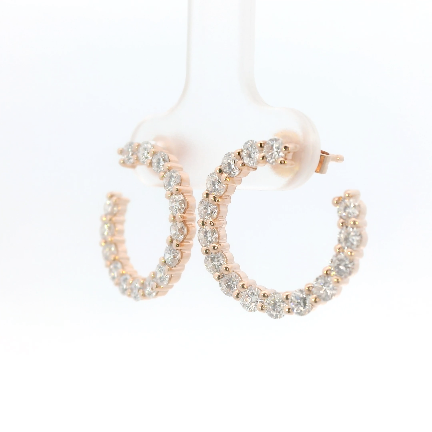 Rose gold hoop earrings with clear gemstones on a white background