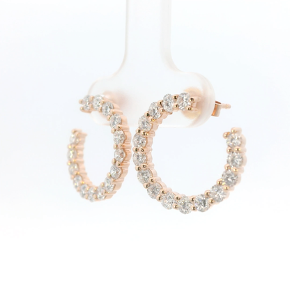 Rose gold hoop earrings with clear gemstones on a white background