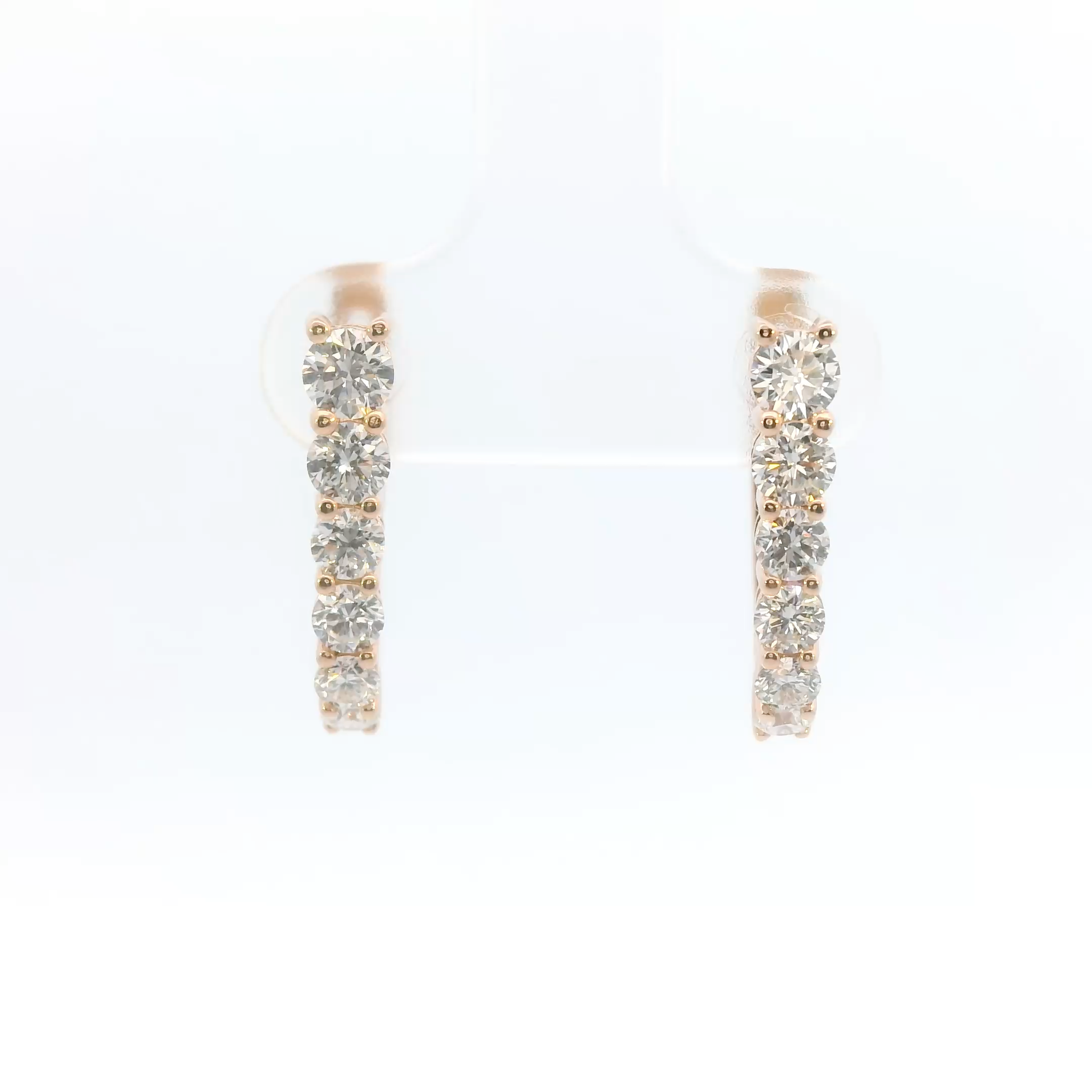 Pair of rose gold hoop earrings with clear gemstones on a white background