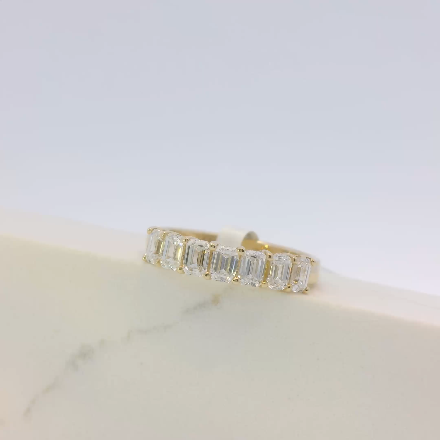 Gold ring with emerald-cut diamonds on a light background