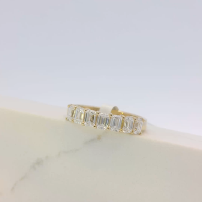 Gold ring with emerald-cut diamonds on a light background