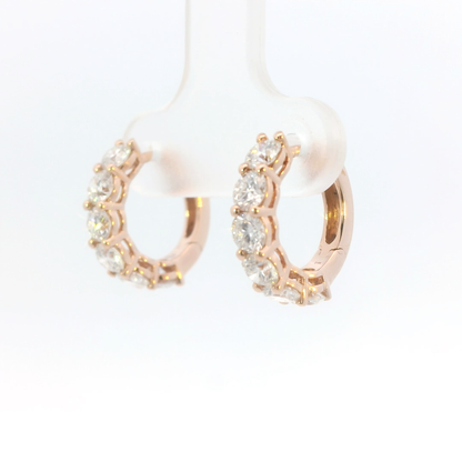 Rose gold hoop earrings with pearls and clear stones on a white background