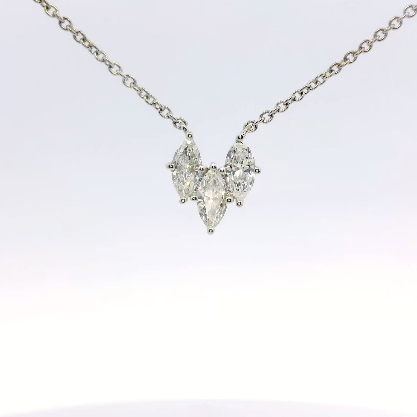 Diamond necklace with three pear-shaped stones on a light gray background