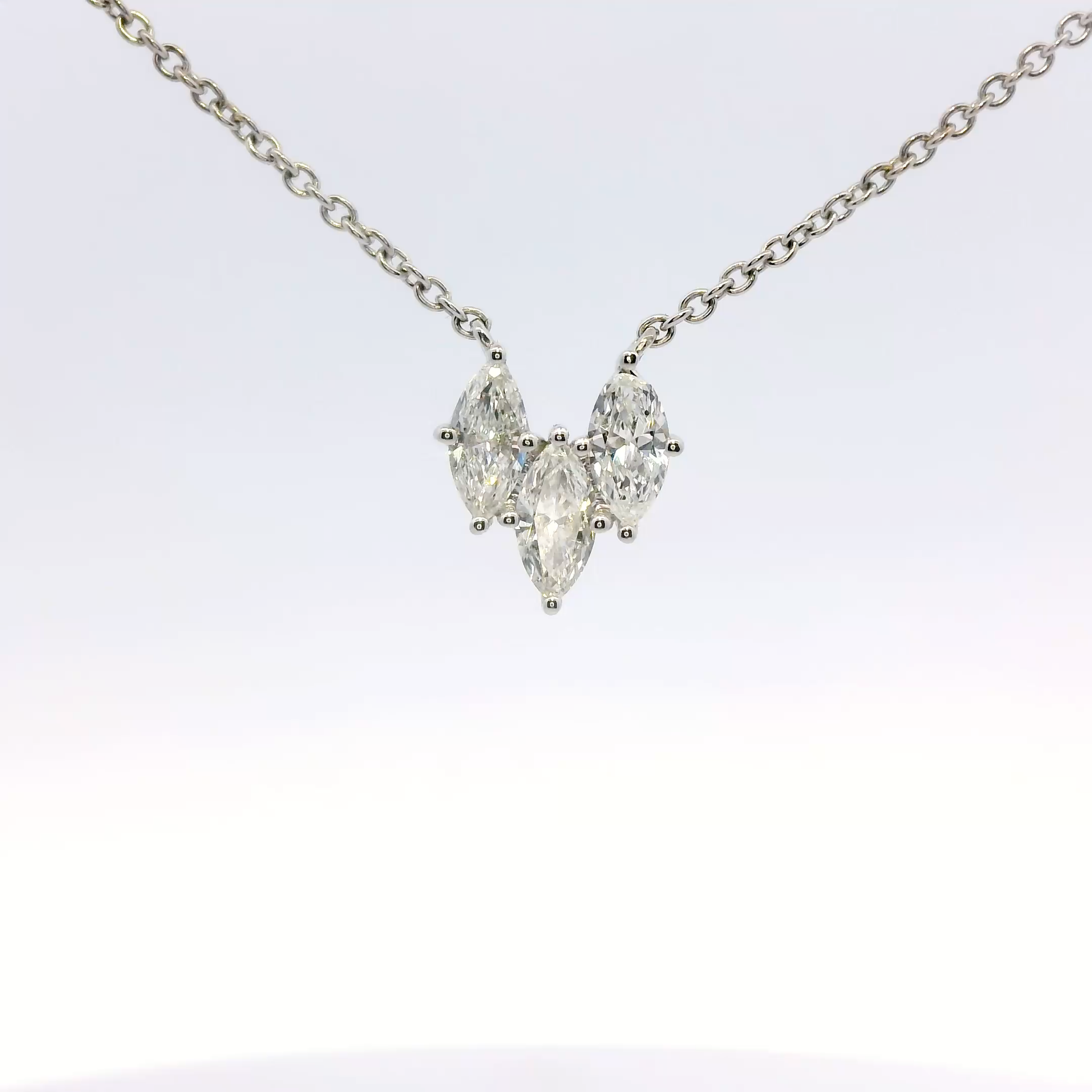 Diamond necklace with three pear-shaped stones on a light gray background