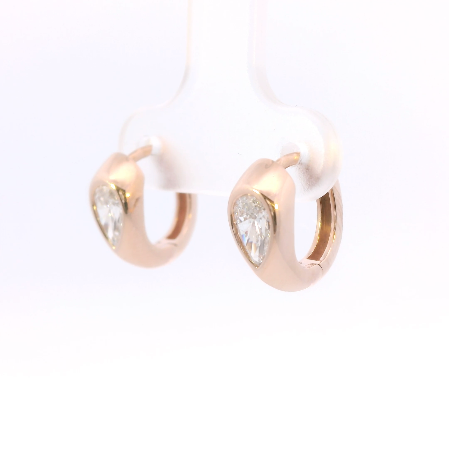 Rose gold hoop earrings with teardrop diamonds on a white background