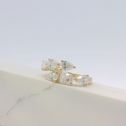 Gold and silver ring with clear gemstones on a marble surface