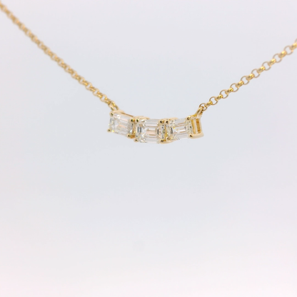 Gold necklace with a diamond pendant on a light gray background