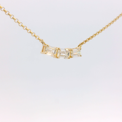 Gold necklace with a baguette-cut diamond pendant on a light gray background