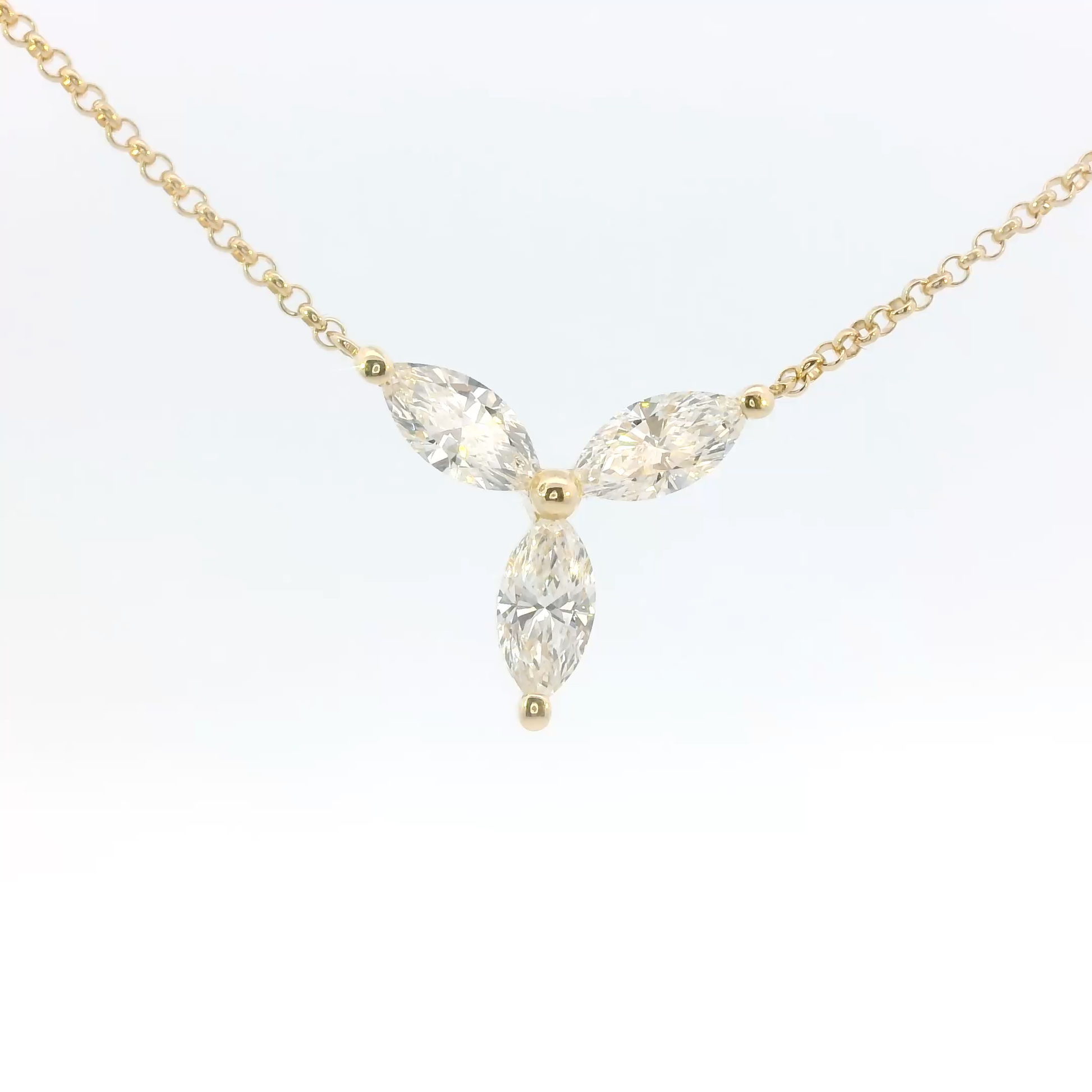 Gold necklace with three clear gemstones on a white background