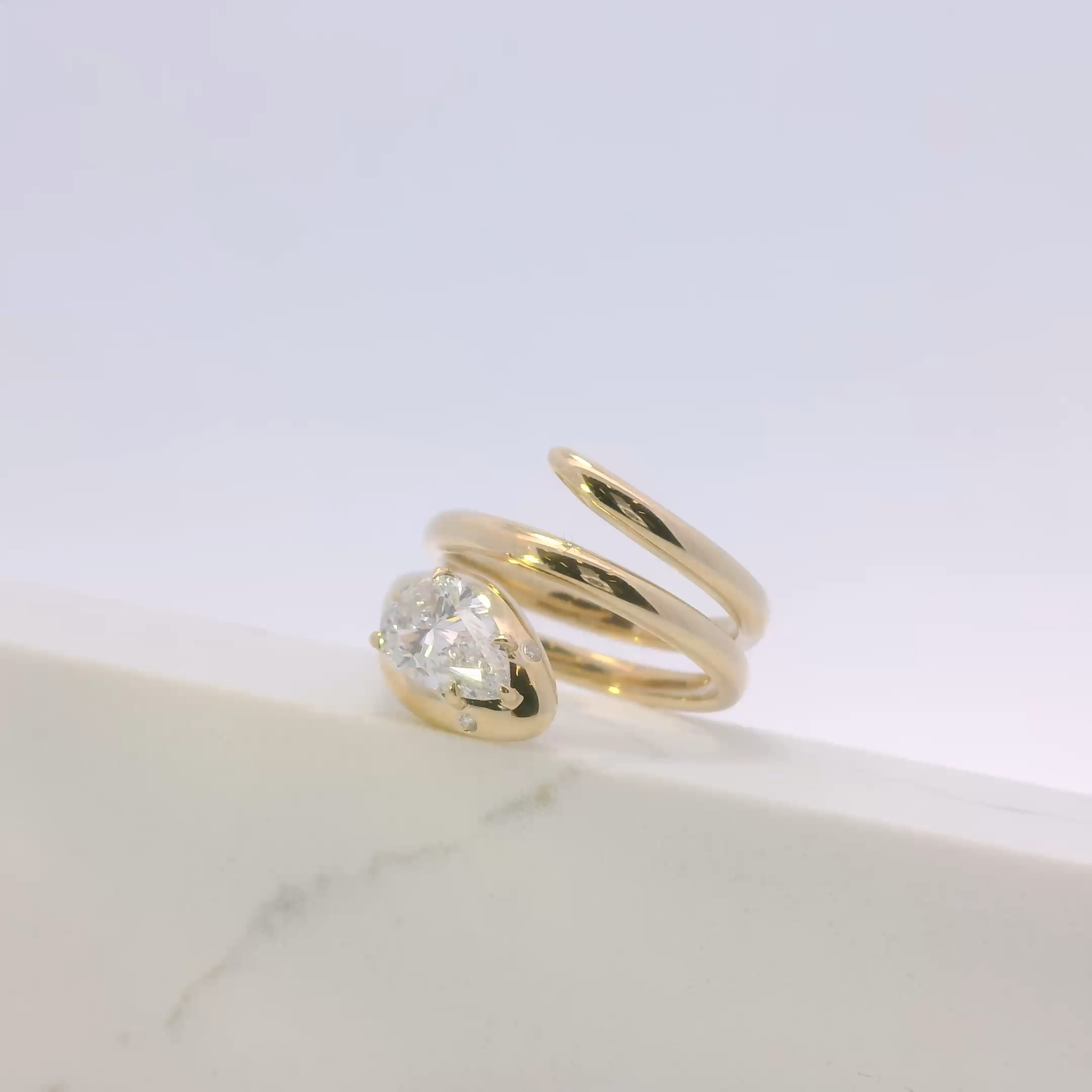 Gold ring with a diamond on a marble surface